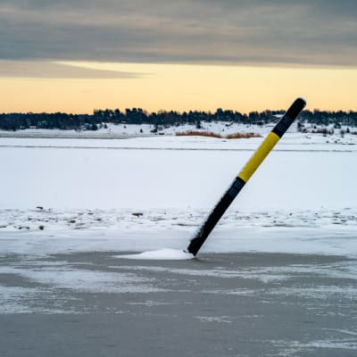 Ett sjömärke står snett på isen.