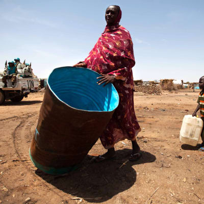 Kvinna bär en vattentank i ett flyktingläger i Sydsudan.