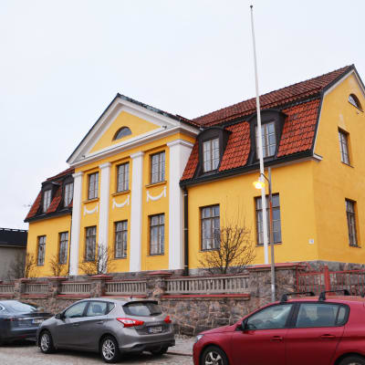 På bilden syns ett stort gult hus med vita detaljer.