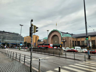 Helsingfors järnväggstation i bakgrunden och en gata med bilar i förgrunden.