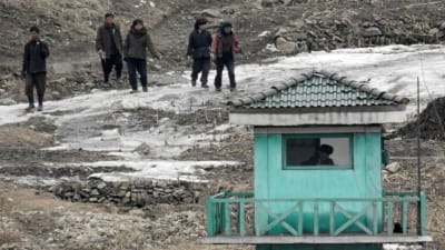 Bild tagen den 7 mars 2016 från den kinesiska staden Dangdong, som gränsar till Nordkorea. På bilden går nordkoreaner förbi en vakt.