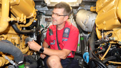 En man sitter inne i motorrummet på en sjöräddningsbåt.