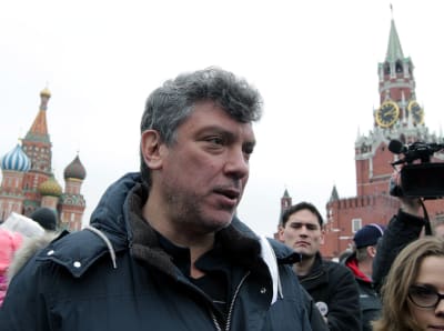 Boris Nemtsov, taustalla Kremliä ja mielenosoittajia. Nemtsovilla parransänkeä ja harmaa tukka. 