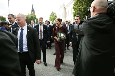 Kronprinsessan Victoria i Lovisa gamla stad med en bukett blommor i handen. Kronprinsessan är omgiven av säkerhetsvakter och fotografer. Bredvid henne går Lovisas stadsdirektör Jan D. Oker-Blom. En bit bakom dem skymtar prins Daniel.