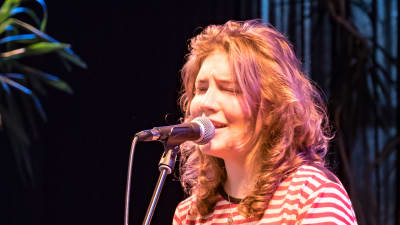 En ung kvinna sjunger in i en mikrofon.