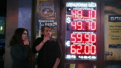 Ryssari Moskva  röker vid en informationstavla som visar valutakurserna 28.11.2014.