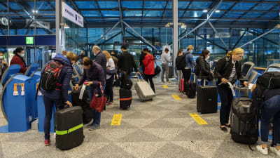 Resenärer med kappsäckar står vid Finnairs check-in-kiosker på Helsingfors-Vanda flygplats.