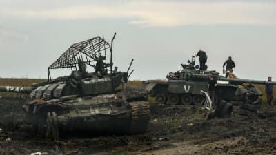Ihmisiä kiipeilee tuhottujen venäläispanssarivaunujen päällä.
