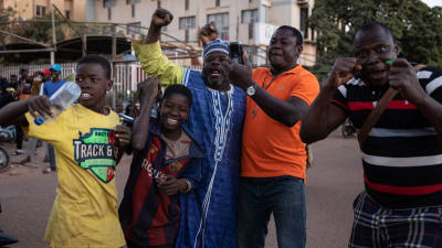 Ett gäng män och pojkar på gatan i Ougadougou jublar och håller upp knytnävarna efter militärkuppen i Burkina Faso.