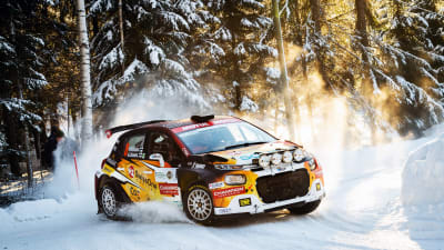 En rallybil kurvar i snölandskap.