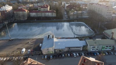 Flygbild över Barkplan i Åbo, man ser en stor plan med glänsande is och bland annat höghus runt. 
