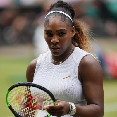 Serena Williams håller i sin racket och tittar nedåt.