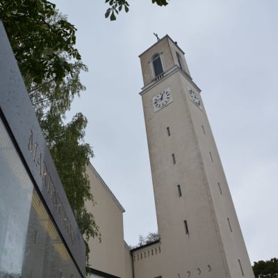 Korkean kirkkotornin huipulla on kellotaulu. Edessä on Martinkirkon opastaulu. 