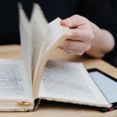 Väitöskirjatutkija Anna Kajander selailee lempikirjansa sivuja, joille joku on aikanaan piirrellyt.