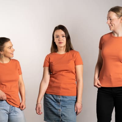Kolmella eri mittaisella naisella sama oranssi t-paita päällä.