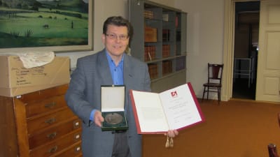Museichef Dan Lindholm visar upp Helene Schjerfbeck-medaljen och diplomet Ekenäs museicentrum EKTA fick av Svenska Kultrufonden.
