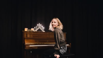 Laulaja Hanna-Maaria Tuomela istuu pianon edessä.