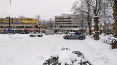 Bilar parkerade i snöigt stadslandskap.