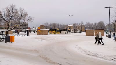 Ett snöigt torg med några bussar.