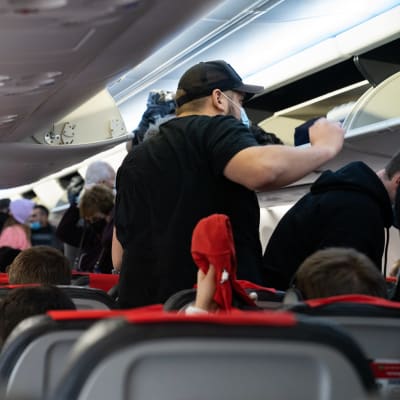 Passagerare som står i gången ombord på ett flygplan.