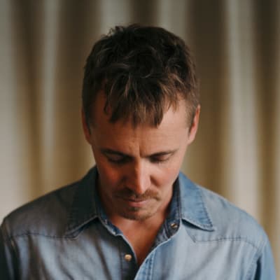 Jasper Pääkkönen sinisessä farkkupaidassa on painanut katseensa alas.