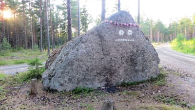 Mårrans ansikte målat på en sten på Pellinge i Borgå skärgård, blomsterkrans på huvudet Tove Jansson100-årsjubileet till ära