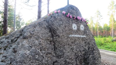 Mårrans ansikte målat på en sten på Pellinge i Borgå skärgård, blomsterkrans på huvudet Tove Jansson100-årsjubileet till ära