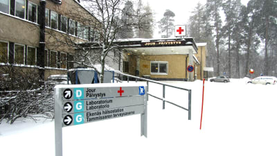 En snöig informationsskylt utanför ett sjukhus i vinterlandskap.