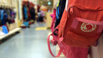 En ryggsäck hänger på en knagg i en skolkorridor.
