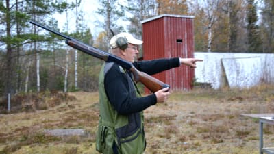 Jägaren och skytten Henrik Gullans står i profil, i händerna håller han ett halvautomatgevär och han har hörlurar på huvudet.