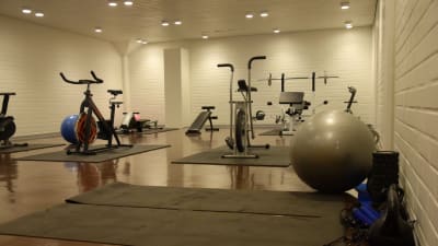 Ett gym med gymnastikmattor på golvet, motionsscyklar och andra motionsredskap.