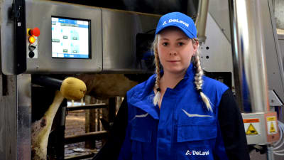 Mjölkbonden Sofia Eriksson står framför mjölkroboten.