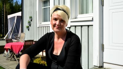 Pernilla Vikström sitter i solen på trappan till hennes hem
