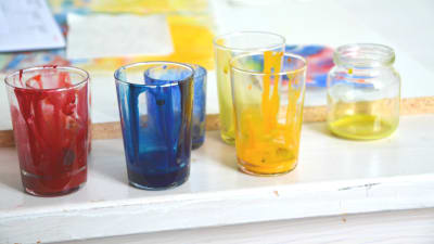 Glas med röd, blå och gul färg på en vit bordskant
