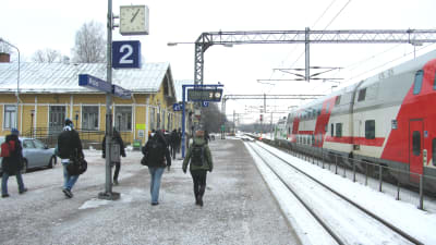 Människor går på perrongen på järnvägsstationen i Karis.