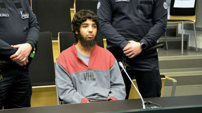 Marockanen Abderrahman Bouanane sitter i rätten med två säkerhetsvakter som står bredvid.