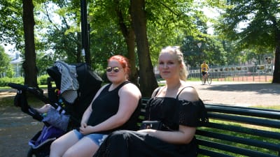 Två kvinnor på en bänk i parken.