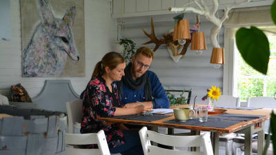 Merja och Jan-Christian sitter vid köksbordet och fyller i blanketter