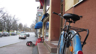 En gata med några parkerade rollatorer och en cykel utanför en dagcentral.