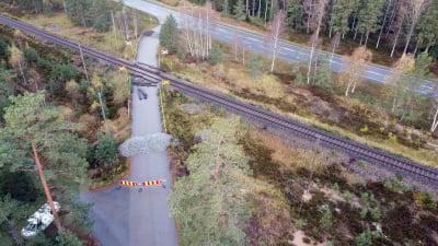Plankorsningen i Skogby där det skedde en olycka i oktober 2017 mellan rälsbuss och militärfordon. Bilden visar platsen från luften med järnväg, grushögar och staket som stänger av korsningen.