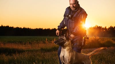 En polis med en schäferhund i solnedgången.