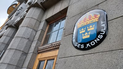 Ovalt skylt med tre kronor och texten Sveriges konsulat på en husvägg