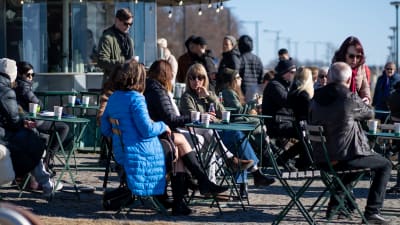 Människor på terrassen på Cafe Kompass vid stranden av Brunnsparken på vårdagjämningen.