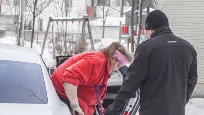 Anita Andersson får hjälp med att stiga ur taxin av chauffören Marko. 