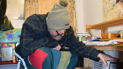 en konstnär iklädd mössa fryser och arbetar i sitt kalla garage