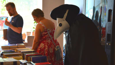 En person utklädd under Finncon tittar på böcker. 