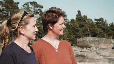 Opettaja Christiane Ala-Nissilä ja suojelubiologi Heidi Arponen seisovat Dalkär-saaren rannassa.