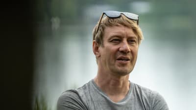 Porträttfoto av man som står nära vatten med en grå t-skjorta