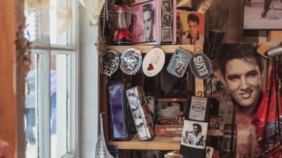 Hylla full med Elvis Presley-saker: strumpor, nyckelringar, askar, foton och böcker.