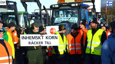 Bönder protesterar med plakat och traktorer i Vasa hamn.